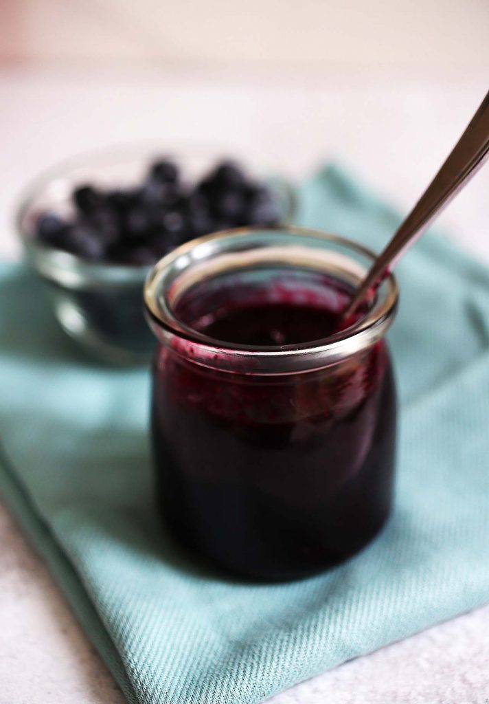 Blueberry sauce in jar with fresh blueberries. 