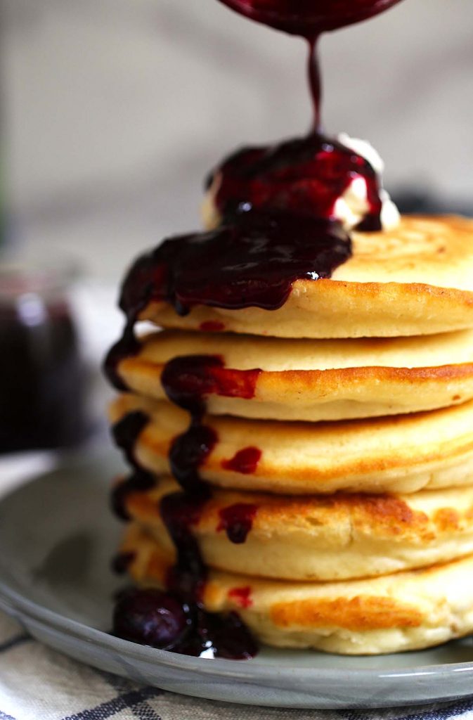 Stack of pancakes with mascarpone cheese and blueberry sauce.