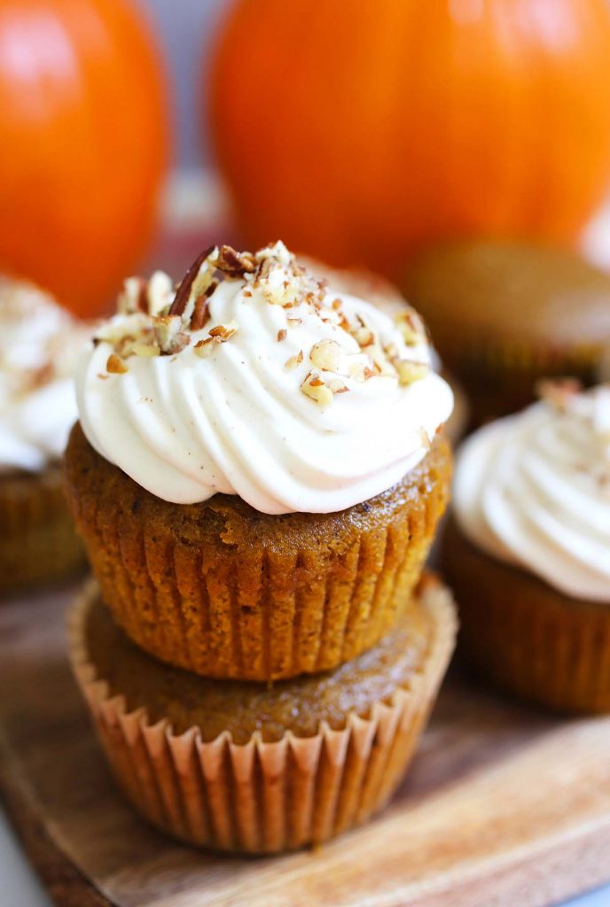 Pumpkin spice muffins with frosting and chopped pecans.