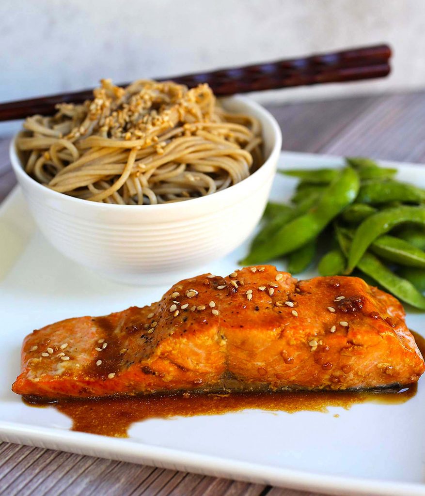 Salmon with soba noodles and edamame on a plate.