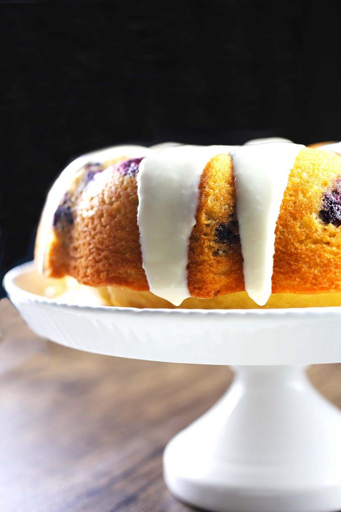 Lemon blueberry cake with cream cheese frosting on stand.