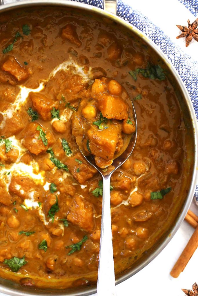 Pumpkin spice curry with chickpeas and coconut cream in pan.