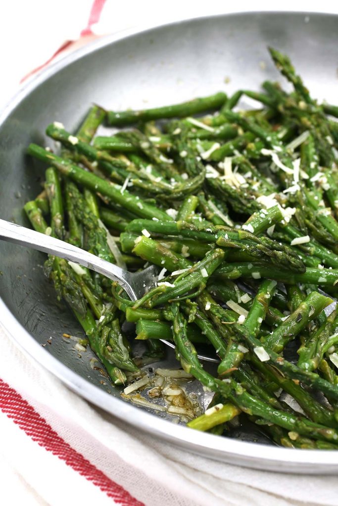 Asparagus with garlic and cheese in pan.