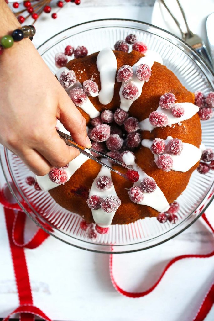 Adding sugared cranberries on top of cake.