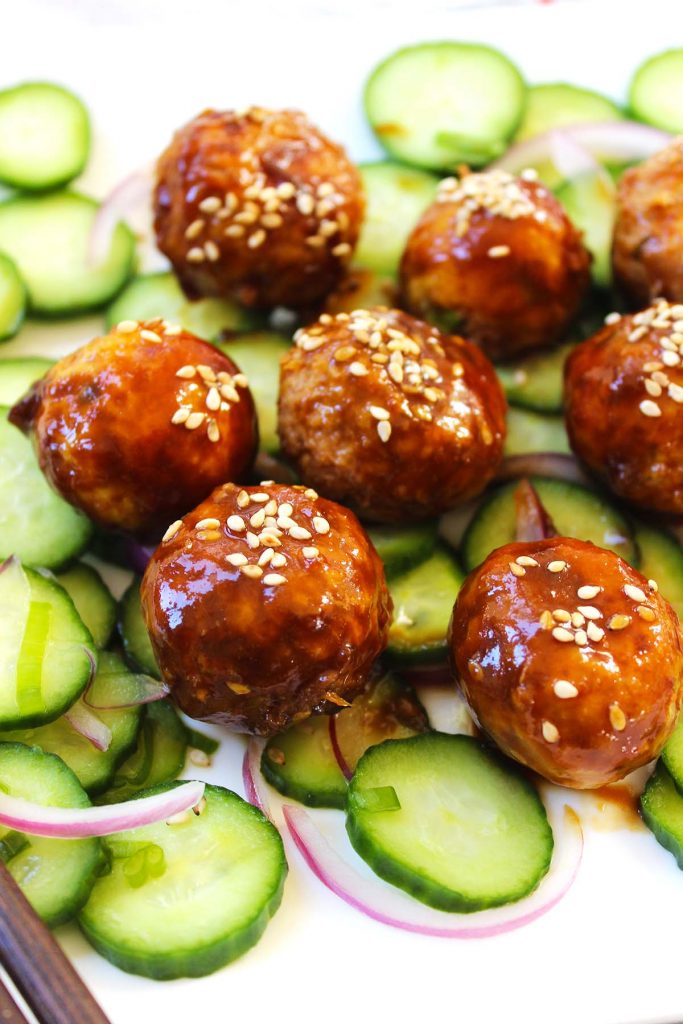 Asian meatballs with cucumber and onion salad on a plate.