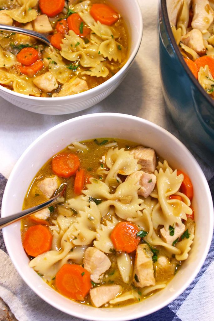 Chicken noodle soup in pot and bowls.